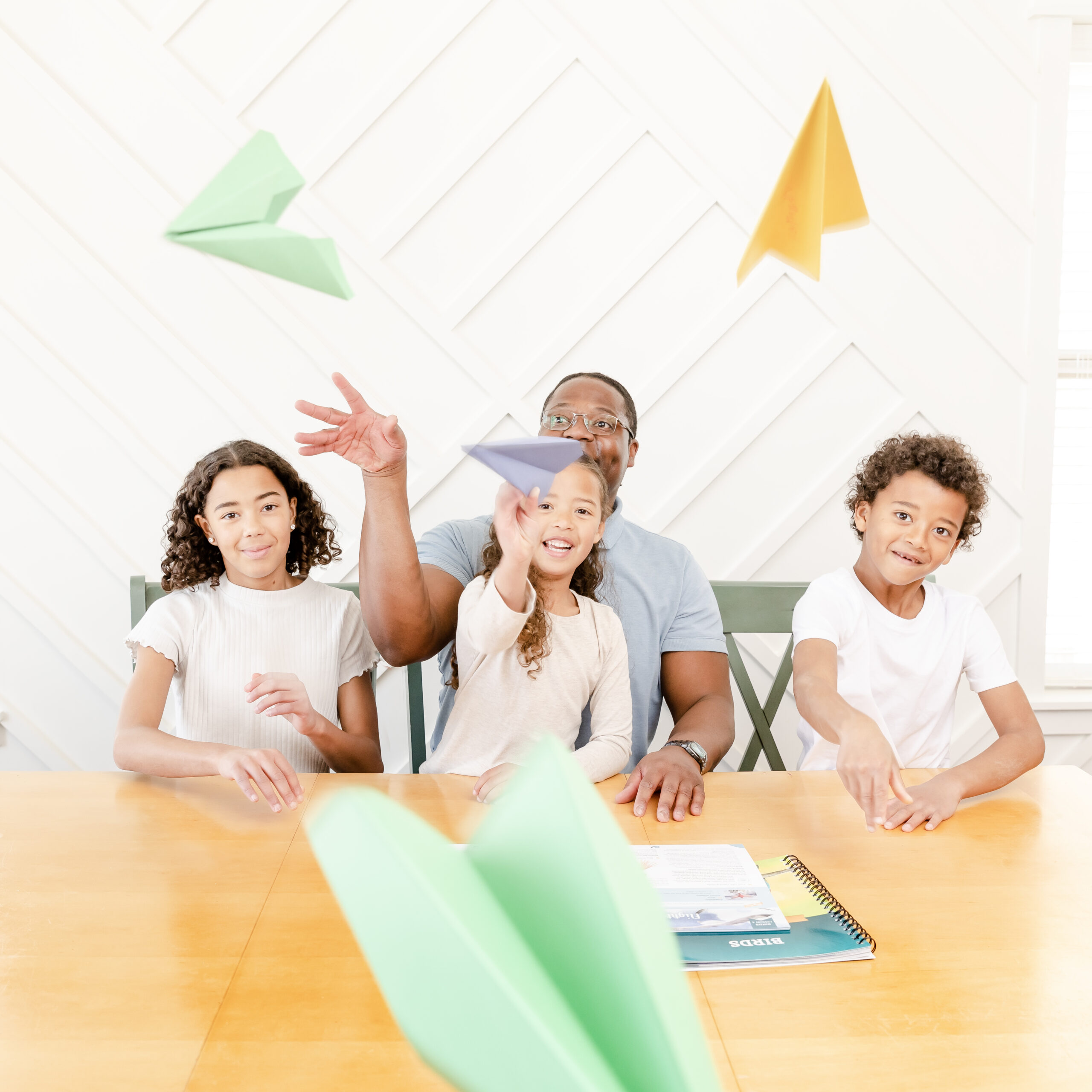 Photograph of Dad and Children Throwing Paper Airplanes for Homeschool Birds Science Unit Study from The Good and the Beautiful